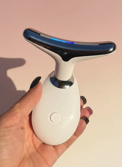 The Glow Lab white and chrome anti-wrinkle facial toning device held in a hand against a soft pink background.