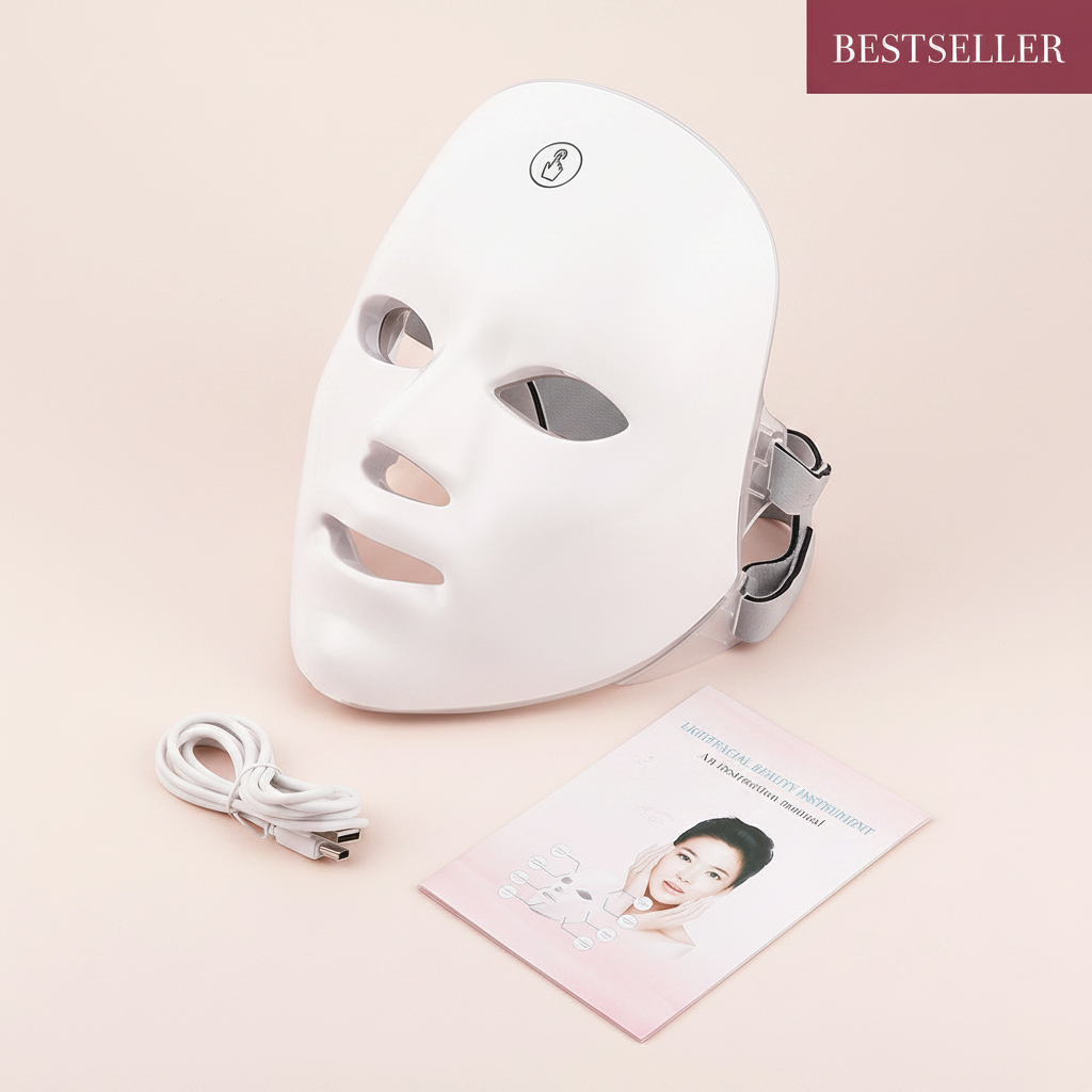 The Glow Lab white LED light therapy facial mask with USB charging cable and instruction manual on a soft background.